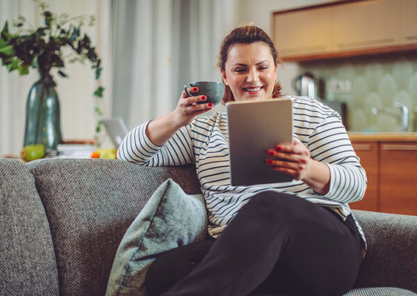 Blonde white woman in stripy jumper looking at Bond Wolfe Auction website on her tablet at home